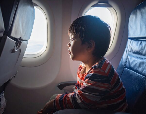 Firefly 여객기 좌석에 앉은 한국인 어린이가 창을 통해 밖을 바라보고 있다. 실내 조명은 매우 어둡다. 126182